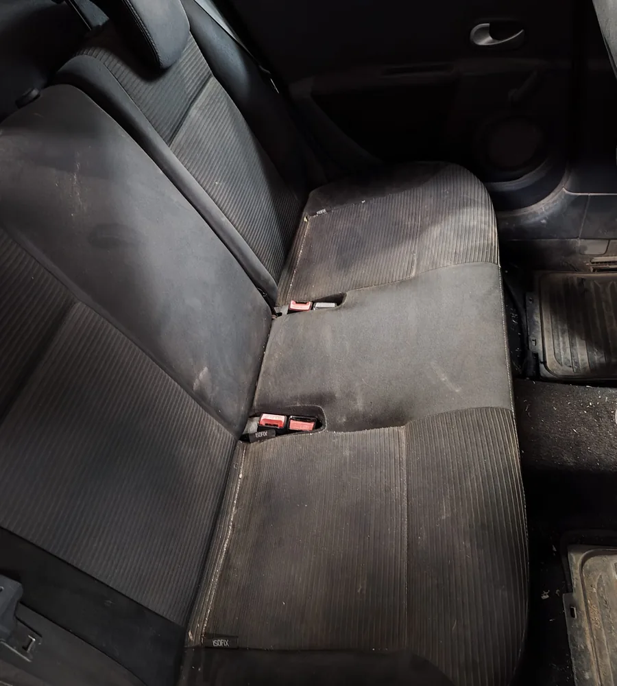 Los asientos traseros y las alfombrillas de un coche antes de la limpieza interior: el tapizado apelmazado y el suelo lleno de barro